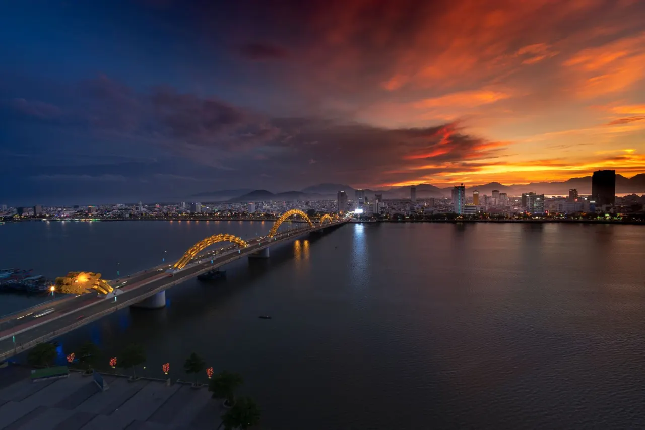 Cầu Rồng rực rỡ ánh đèn vàng lúc hoàng hôn, bầu trời cam đỏ trên sông Hàn